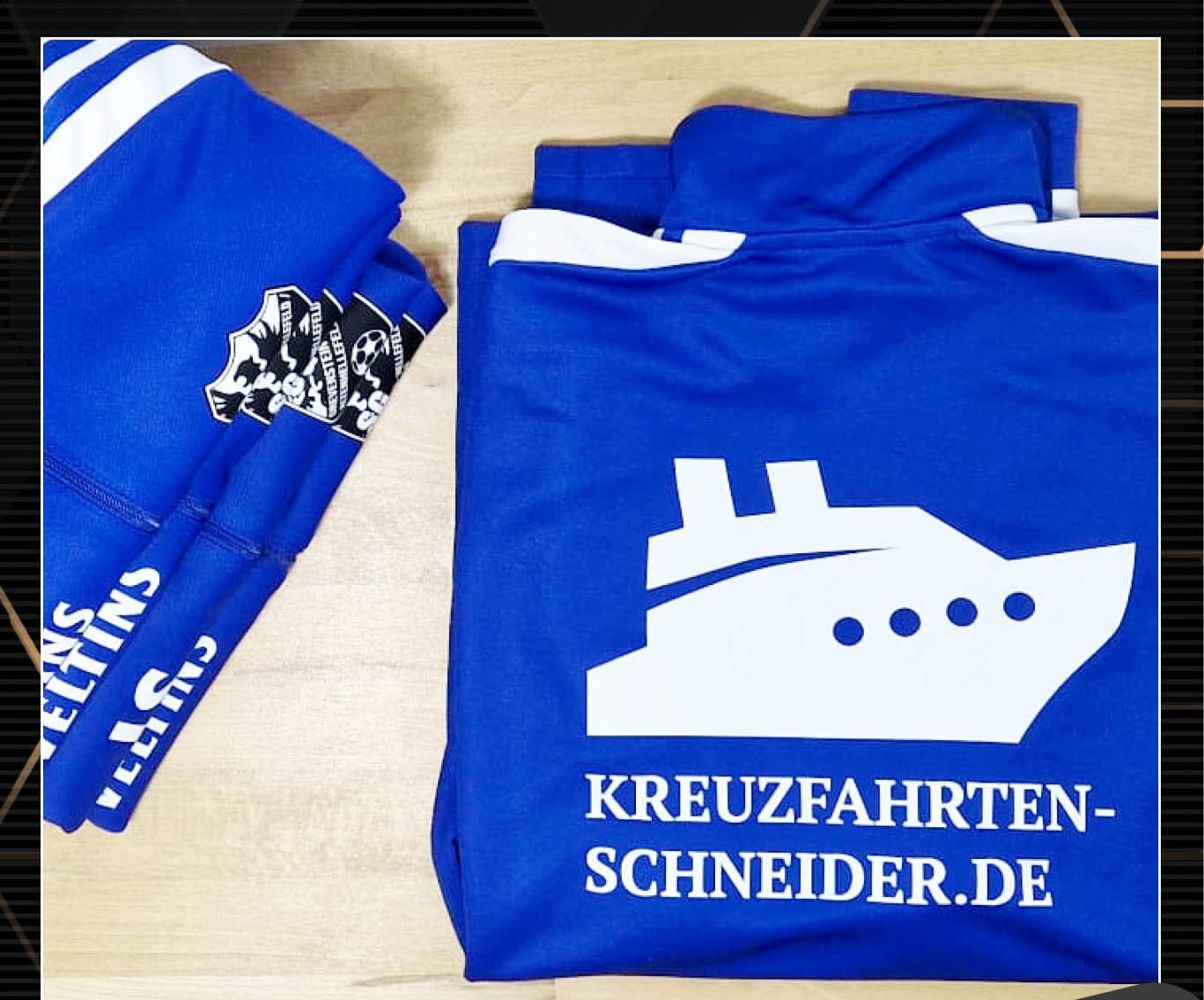 Gestapelte blaue Vereinsoberteile mit großem Sponsoren-Rückenmotiv
